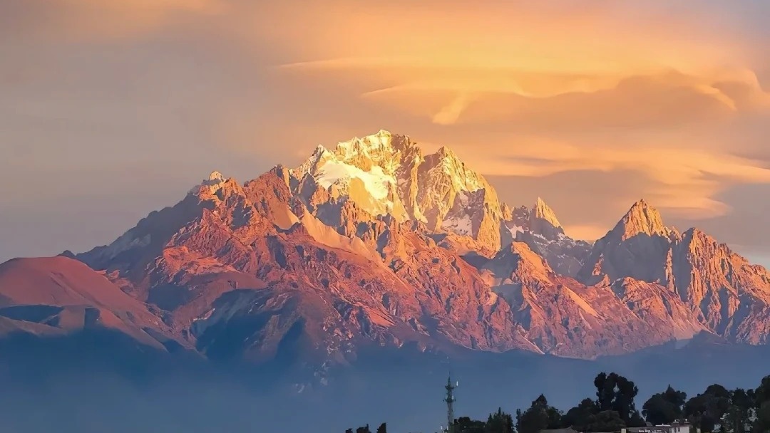 Ancient traditional tiled village rooftops bathed in golden sunrise beneath majestic snow mountain summits